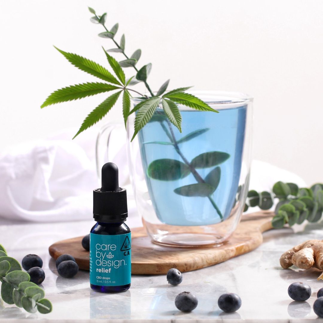 care by design relief tincture with a glass with blue liquid and a cannabis leaf in the background