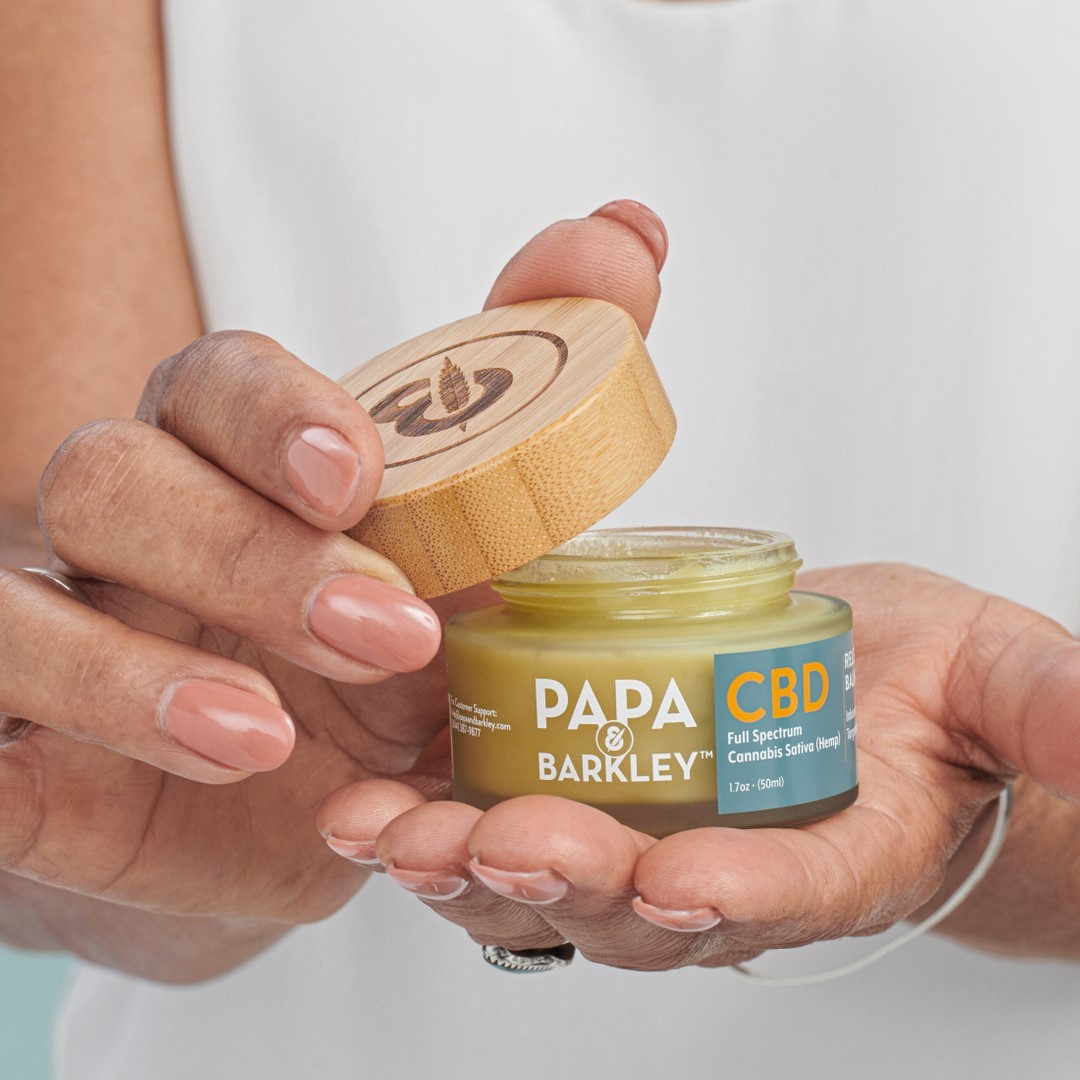 Close up of hand holding Papa and Barkley CBD topical