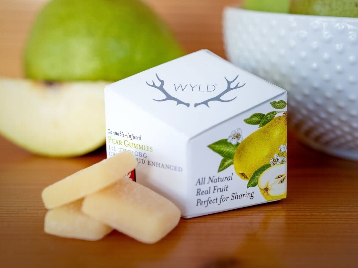 wyld pear gummies sit on a table with fresh pear