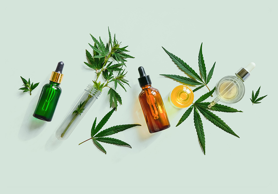 tincture bottles and cannabis leaves on green background